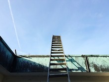 Low Angle View Of Metallic Ladder Leaning On Retaining Wall Against Sky