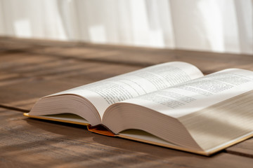 A thick book with open hardcover on a wooden floor