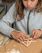 Preteen girl doing popsicle stick craft.