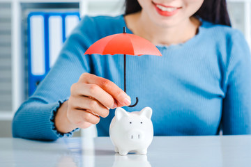 Young asian woman hand hold umbrella toy to protect the home and money for saving money and house and real estate property protection concept.