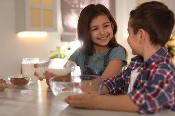 Wall Mural - Cute little children cooking dough in kitchen at home