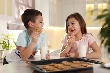 Wall Mural - Cute little children eating cookies with milk in kitchen. Cooking pastry