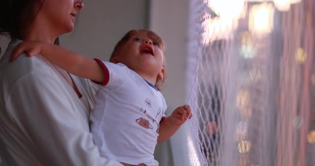 Wall Mural - One year old baby holding into safety net at apartment balcony