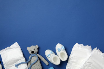 Wall Mural - diapers and baby accessories on blue background, flat lay. space for text