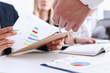 © H_Ko - Group of people deliberate on problem with clipboard pad closeup. White collar check money papers, stock exchange market, earnings list, partnership agreement discussion concept
