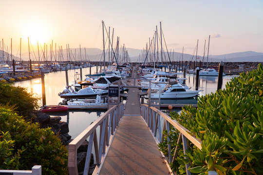 sunset marina. boat & yacht jetty bridge into sea. airlie beach boat harbour waterfront sunset view.