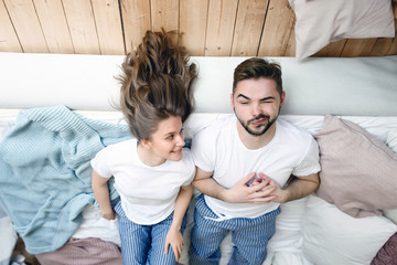 Young couple in love lies on the bed close to each other and smilng