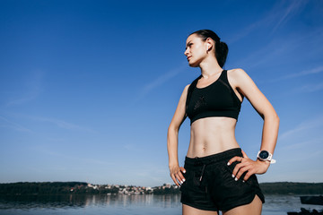 Young sports fitness woman make stretching exercises at the beach outdoors listening music with earphones.