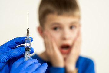 Sticker - Doctor preparing vaccination injection with a syringe to an afraid child boy. Vaccination of children at school concept.