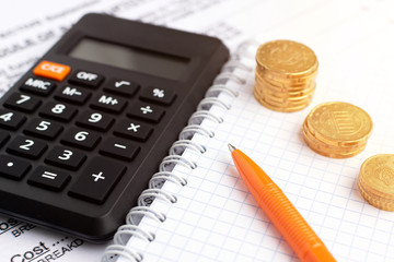 Home budget concept. Close-up coins, pen, calculator at financial report and notebook.