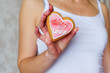© Olha - Heart shaped cookies in pink chocolate, top view. Gentle cute gift and dessert treat by February 14, Valentine's Day, a sweet gift for lovers. In woman female hand
