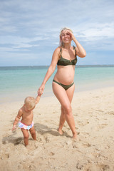 Happy pregnan mother with little daughter on beach