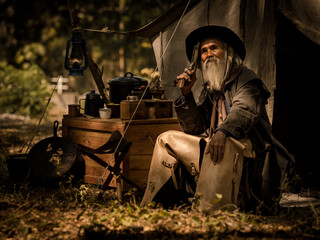 A senior cowboy sat with a gun to guard the safety of the camp in the western area