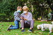 © progat - Grandmother and little kid playing with a smartphone in the backyard while wearing protective masks due to coronavirus outbreak