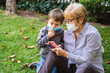 © progat - Grandmother and little kid playing with a smartphone in the backyard while wearing protective masks due to coronavirus outbreak
