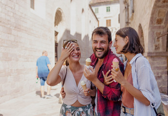 Wall Mural - Smiling friends eating ice cream and walking on street