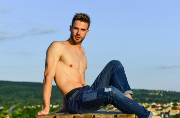 Pure perfection. male fashion model on sky background. summer relax outdoor. athletic sportsman has sexy body. muscular man at sunset. macho man has naked torso. sexy man undressed in jeans