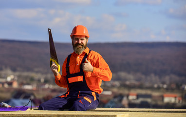 Construction carpentry. Man builder wear uniform and hard hat for protection. Carpentry concept. Hard labour on sunny day outdoors. Bearded construction worker. General construction experience