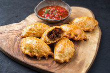Traditional South American Empanada De Carne Offered With A Chili Dip As Closeup On A Rustic Wooden Board
