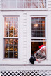 © LÈa Jones/Stocksy - Boy with Santa hat in window on Christmas