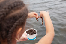 Cute Young Girl With Cornrow Braids Examining The Bait Worms While On The Boat During A Fishing Trip