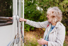 Senior Woman Opening Door Of Caravan