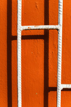 White Fence And Shadow Over Orange Wall