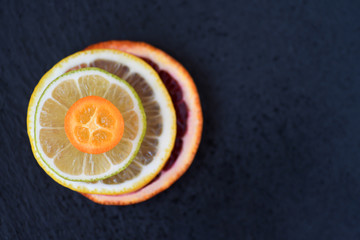 Wall Mural - Ripe fresh red Sicilian blood orange lemon lime kumquat fruit macro dark green background. Juicy sweet sour citrus pulpy thin slice pile stack. healthy nutritious food concept, vegetarian vegan diet