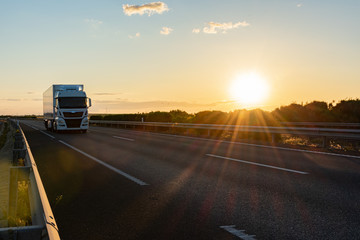 Wall Mural - Truck with refrigerated semi-trailer driving on a highway with the sun low in the evening.