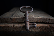 Three Old Rusty Keys Stand On Old Wooden Board Against A Dark Background