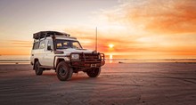 Outback Relaxing Adventure With 4WD Vehicle At The Beach Of An Ocean At Sunrise 