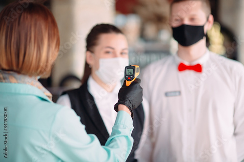 The Manager of a restaurant or hotel checks the body temperature of the staff...
