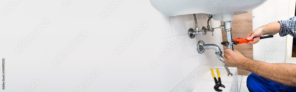 Male Plumber Fixing Sink In Bathroom - obrazy, fototapety, plakaty 