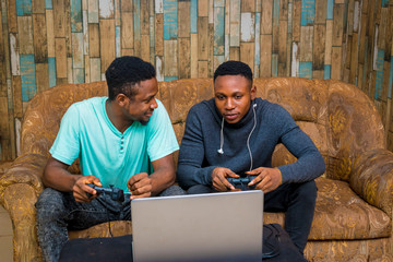 Wall Mural - young black men playing a video game on a laptop at home