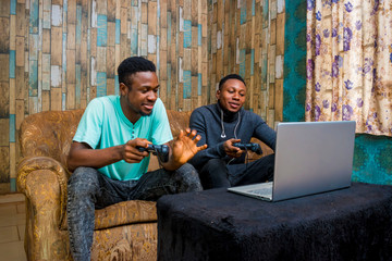 Wall Mural - young black men playing a video game on a laptop at home