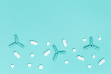 White pills shaped of molecule, virus, or bacteria on mint colored surface. Mock up for advertising, web background. Medical, pharmacy and healthcare concept. Copy space. Flat lay.