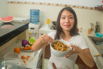 Sticker - young beautiful and happy Asian Japanese woman at home kitchen preparing lunch seasoning dish smiling cheerful in healthy nutrition and cooking hobby concept