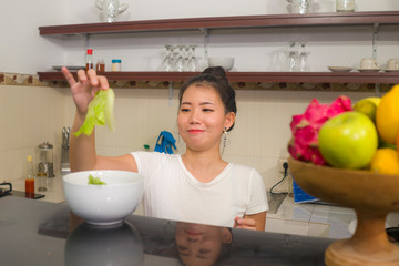 Sticker - young beautiful and happy Asian Japanese woman at home kitchen relaxed preparing vegetables meal smiling cheerful in healthy nutrition and cooking hobby concept