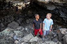 Two Smiling Boys Having Fun Exploring A Large Rocky Cave Together. Boys Will Be Boys And Will Always Find The Next Adventure