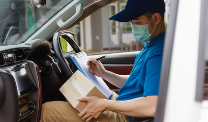 Wall Mural - Asian delivery courier young man driver inside the van car with parcel post boxes checking amount he protective face mask, under curfew quarantine pandemic coronavirus COVID-19