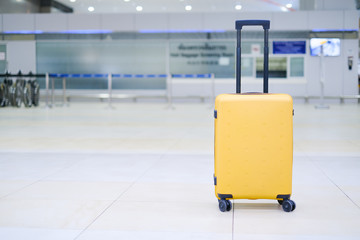 Close up mock up brand tag or name tag tied to yellow thick suitcase, concept of product logo design template on travelling tourism, travel through destination in airport, with blur bright background