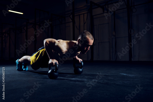 Foto Athletic man exercising kettlebell push-ups at gym