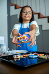 Selective focus on the decorated cookie holding by blurred smiling girl in background