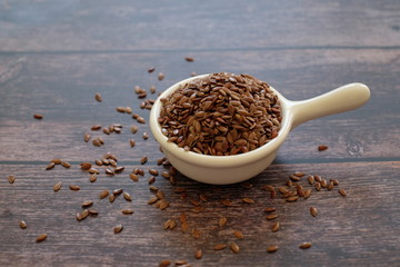 Wall Mural - Brown Flax seeds or Linseeds or Common flax in the white bowl isolated on wooden background. Flax seeds are rich of omega fat.