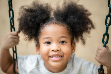 Happy African American little girl smiling look at camera at playground in the park