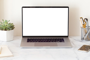 Laptop with blank white screen on home office desk interior. Stylish workplace mockup table view. 