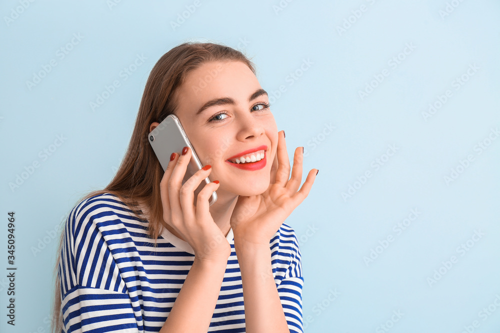 Beautiful young woman talking by phone on color background