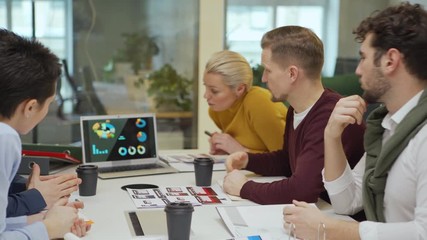 Wall Mural - Zoom out shot of business team discussing financial analysis charts presented on laptop screen during meeting in boardroom