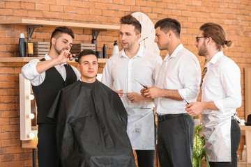 Canvas Print - Professional hairdresser teaching young men in salon