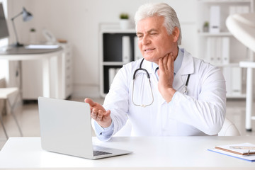 Canvas Print - Male doctor giving a consultation online in clinic